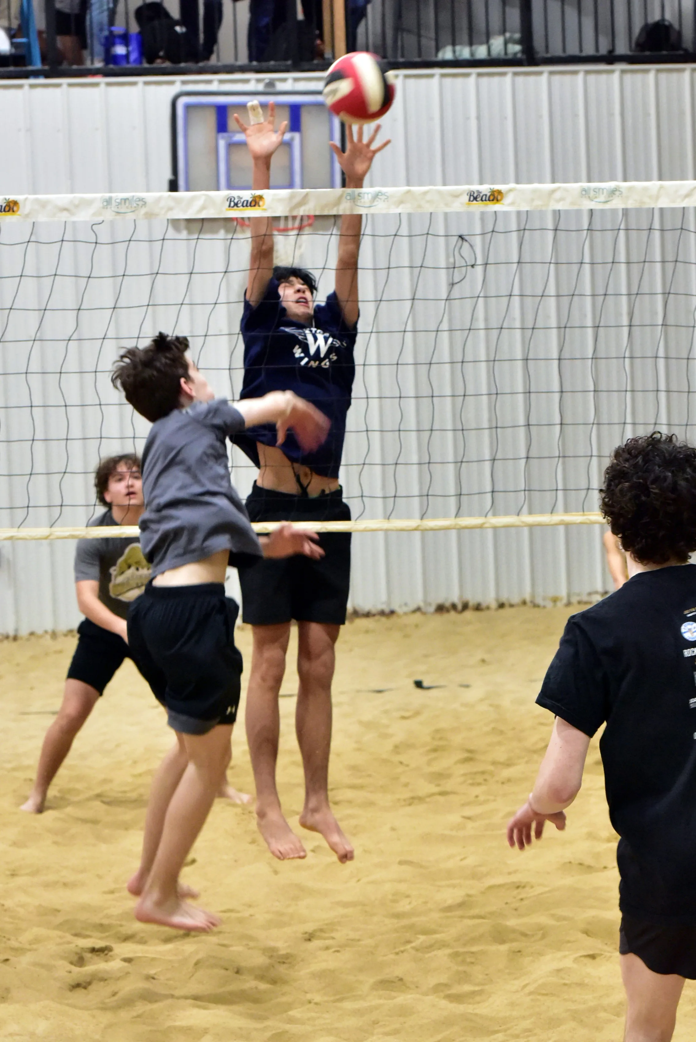 Boys volleyball action at the net during a beach session